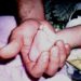 A photo of a father's hand close up gently cradling their infant's foot