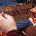 A shimmering "GOLDEN TICKET", the size of a large "Wonka Chocolate Bar" is held in the hands of an awestruck young boy named Charlie.